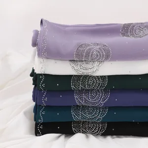 Detail shot of stacked chiffon scarves featuring sparkling rhinestone swirl patterns and colors.
