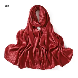 Red satin jacquard leaf pattern long scarf detail view, soft breathable fabric.