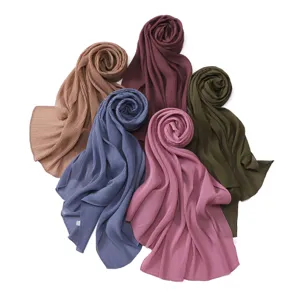 Detail view of multicolored pleated chiffon hijabs, showcasing delicate shimmer fabric.