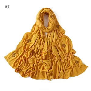 Detailed view of the yellow long scarf with elegant gold rhinestone cross details and soft fabric.