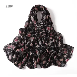 Vue détaillée de l'écharpe en mousseline imprimée florale, tissu doux et fond noir.