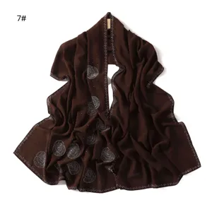 Detail view of the brown chiffon scarf showing rhinestone rose patterns and drape fabric quality.