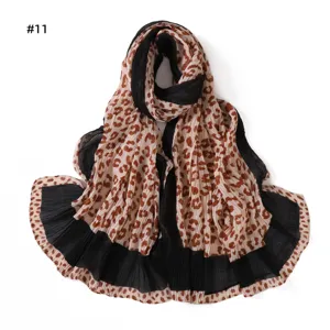 Close-up of pleated leopard print scarf detail showing soft textured fabric and color blocks.