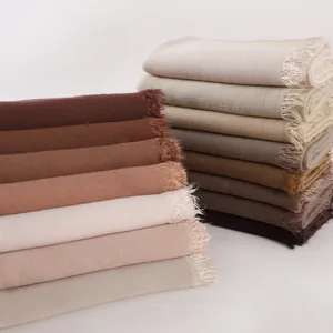 Close-up detail of soft elastic rayon wrinkled long scarves stacked neatly with fringe edges.