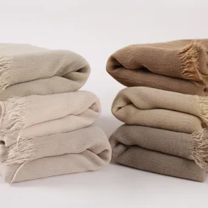 Close-up view of soft wrinkled rayon scarves with chic fringe details in neutral tones.