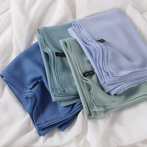Gros plan détail d'un foulard hijab en mousseline unie douce, texture lisse, empilé.