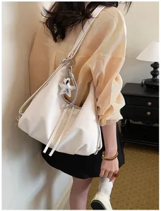Détail de sac bandoulière de trajet blanc polyvalent avec design souple et pendentif étoile.