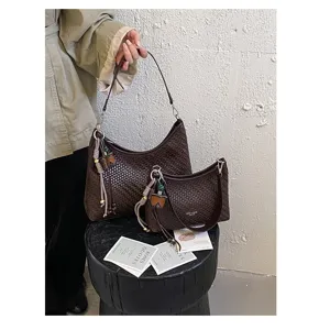 Vue détaillée de l'ensemble de sacs à aisselle tressés marron foncé avec de beaux charms.