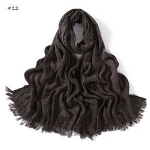 Detailed view of brown crinkled slub cotton scarf with frayed edges and fine texture.
