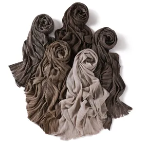 Detailed view of soft pleated crinkle fringe scarves in rich earth tone brown and beige.