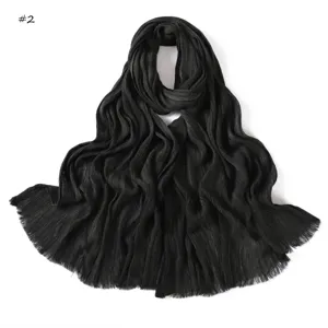 Detailed view of the black pleated long scarf with fringed edges, showing fine fabric texture.