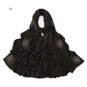 Detailed view of the dark green rhinestone embellished jersey hijab scarf with swirl pattern.