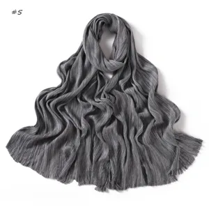 Detailed view of a grey pleated soft long scarf with frayed edges, fine crinkled texture.