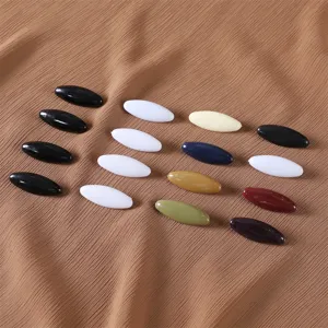 Gros plan détaillé d'épingles à hijab ovales colorées et d'épingles de sécurité aux teintes variées.