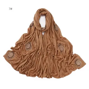Close-up detail of the brown cotton scarf featuring sparkling rhinestone spiral patterns.