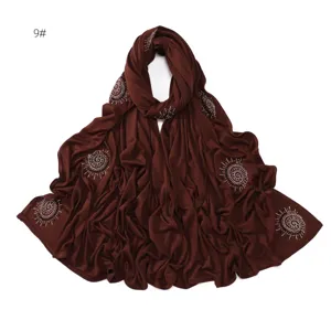 Brown rhinestone embellished detail shot of long scarf, cotton fabric texture display.