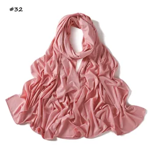 Detalle en primer plano de bufanda de jersey rosa elástico, textura suave y caída fluida.