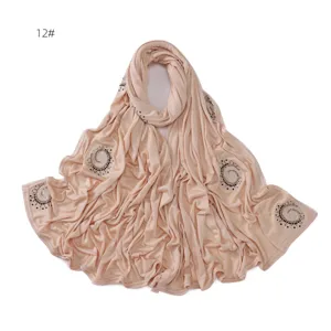 Detail shot of the sparkling rhinestone swirl embellishment on the light beige cotton scarf.
