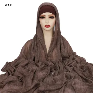 Dettaglio in primo piano della sciarpa hijab lunga stropicciata marrone e cuffia.