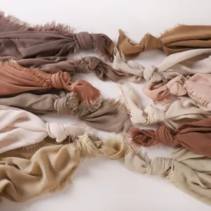Detailed view of soft crinkle long scarves with fringe ends in various neutral earth tones.