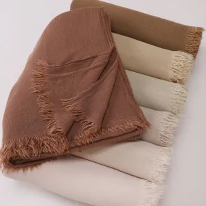 Close-up of soft wrinkled rayon long scarves featuring fringed ends in various solid earth tones.