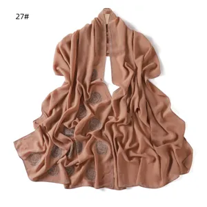 Detailed view of a elegant beige chiffon scarf with sparkling rhinestones and rose pattern.