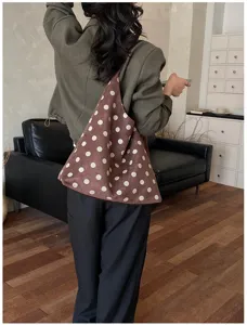 Detail shot of the fashionable brown polka dot suede shoulder tote bag worn by model.