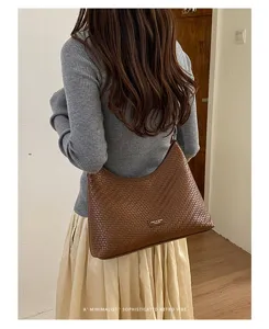 Vue détaillée du sac porté épaule marron tressé, affichant une texture et une grande capacité.
