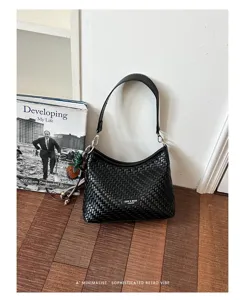 Gros plan d'un sac porté épaule tissé noir élégant dans un décor rétro minimaliste chic.