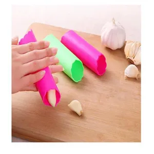 Silicone garlic peeler tube kitchen tool detail showing manual peeling process on wooden board.