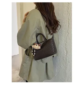 Detailed view of the dark brown woven crossbody dumpling bag with cute bear charm and strap.