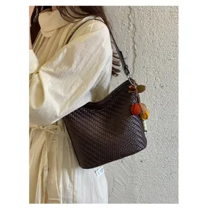 Close-up detail of vintage woven shoulder bag in dark brown with charms and retro style.