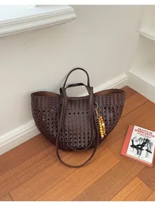 Detailed view of dark brown woven cutout large capacity shoulder tote bag with wooden beads.