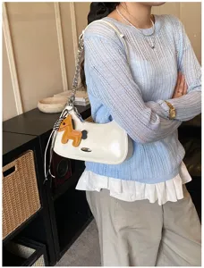 Borsa a spalla in pelle verniciata bianca con ciondolo a forma di cavallo e catena.
