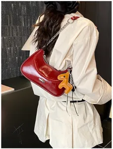 Borsa a tracolla lucida rossa con cinturino a catena di metallo e ciondolo cavallo in pelle.
