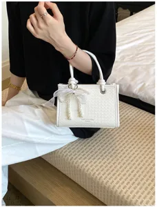 Gedetailleerde close-up van de witte gewoven handtas voor vrouwen met elegante parelhanger.