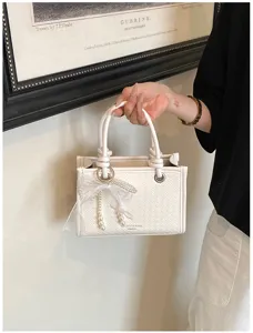Gedetailleerd overzicht van een witte geweven handtas met een elegante parel-strik.
