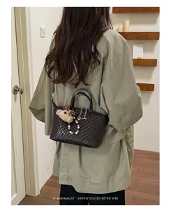 Detailed view of the dark brown woven crossbody dumpling bag with cute bear pendant accessory.
