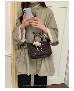 Retro woven dumpling handbag for women, stylish crossbody tote with cute bear pendant, chic fall bag.