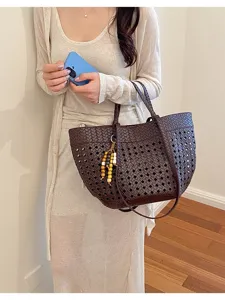 Detailed view of dark brown woven leather tote bag with wooden bead charm in daily wear style.