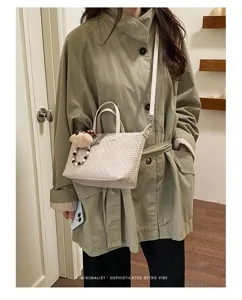 Detail shot of stylish woven dumpling shoulder bag in beige, featuring cute bear charm accessory.