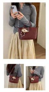 Detail view of the stylish dark red woven handbag featuring cute teddy bear charm and strap.