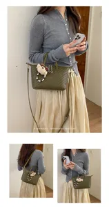 Green woven tote bag detail showing the elegant leather texture and cute bear charm pendant.