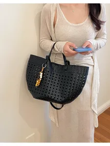 Black woven leather tote bag for women, large capacity shoulder bag with charm detail.
