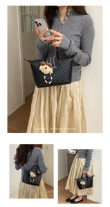 Detailed view of the black woven dumpling handbag with cute bear keychain for women's daily commute.