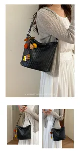 Detail shot of black woven hobo shoulder bag with charming leaf pendant, versatile style.