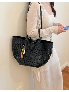 Black woven hollow tote bag worn by model, large capacity retro commuting shoulder bag style