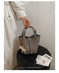 Grey leather bucket handbag for women, stylish minimalist basket tote bag with lock and charm.