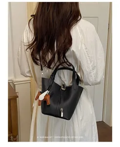 Detail view of black leather bucket bag featuring metal lock and cute charm for women.
