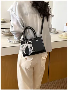 Gedetailleerd overzicht van de elegante zwarte handtas met een mooie parel strik.